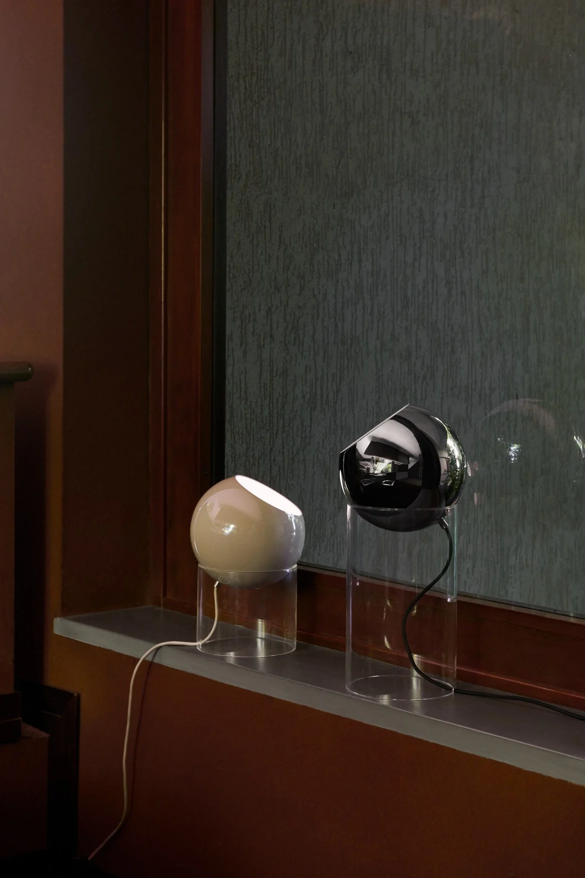 On a window sill stand two Topan table lamps in different sizes from &Tradition in beige and black.