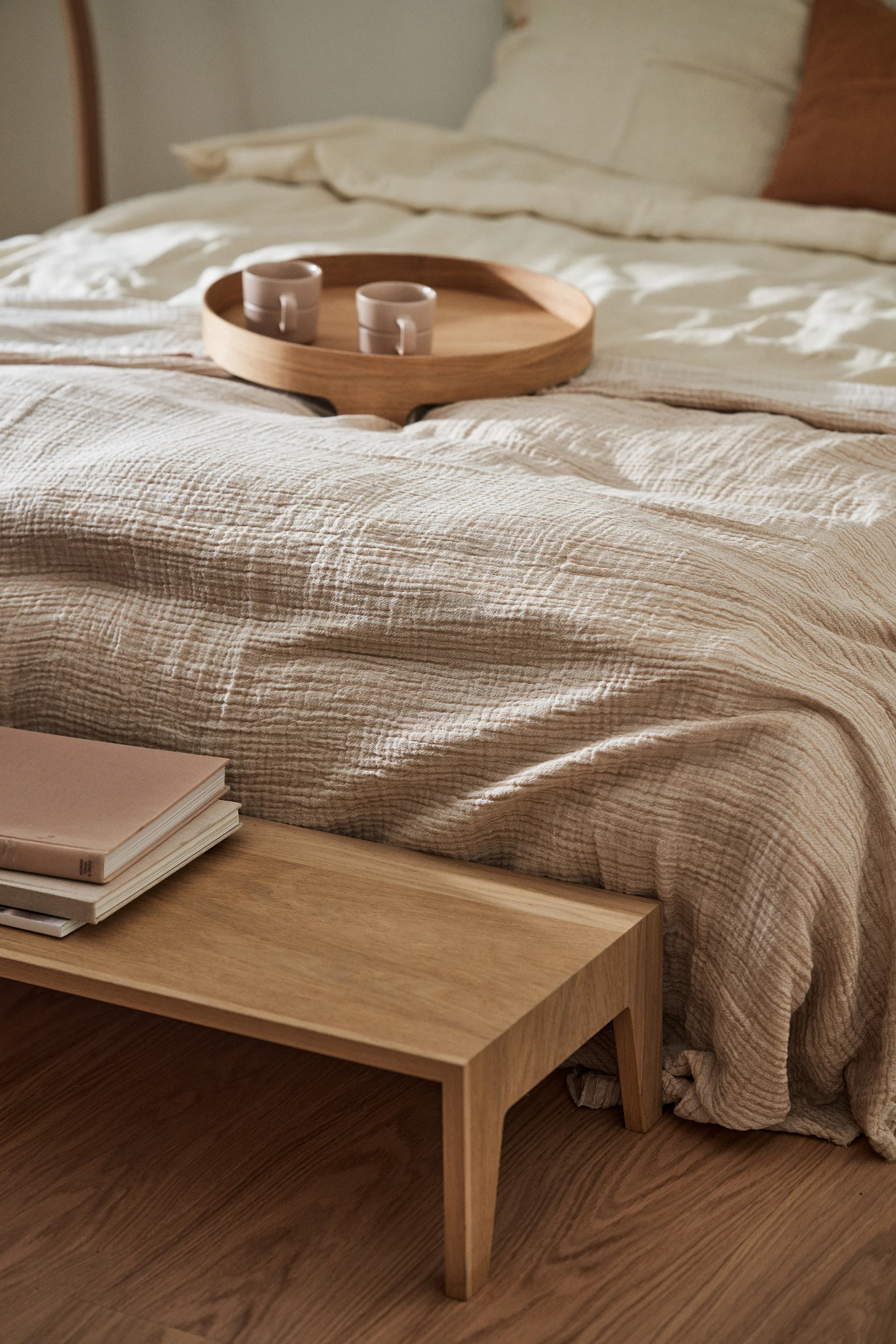 Feng Shui for the bedroom: here you see a calming beige bedroom with a textured bedspread and a wooden tray. 