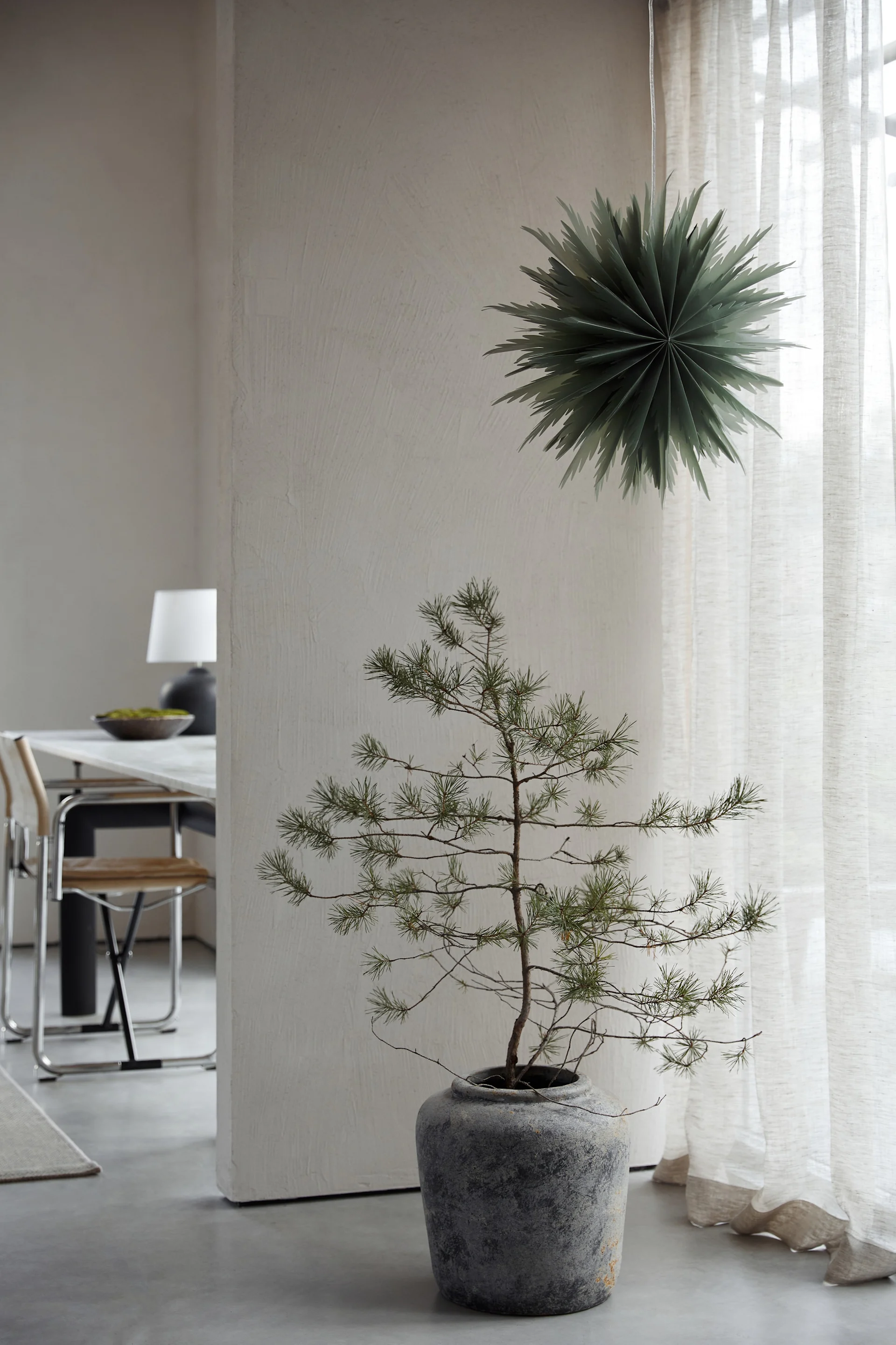 Minimalist Christmas decor like the Oslo paper Christmas star from Watt & Veke. Seen here hanging in the window of a neutral coloured living room. 