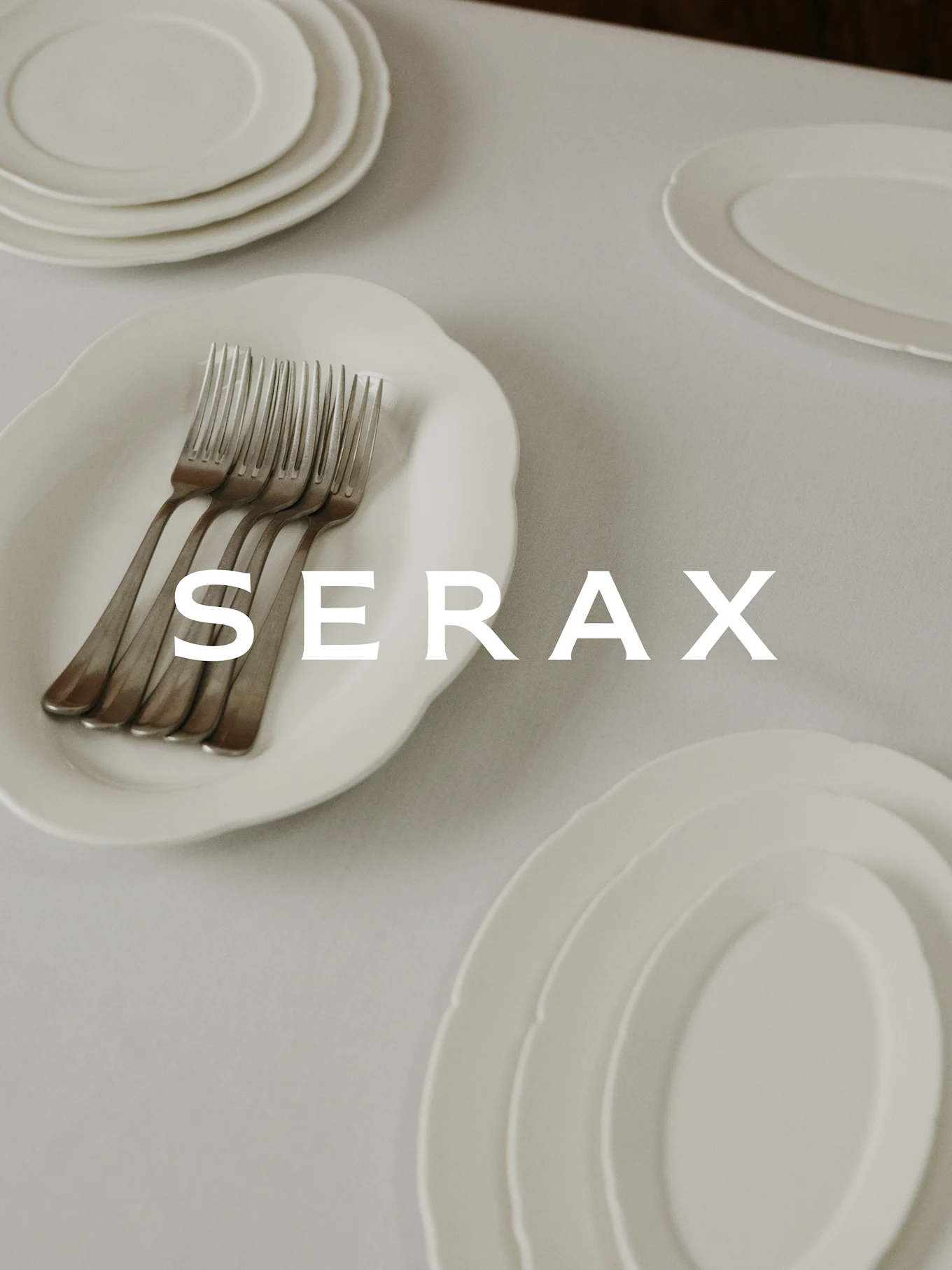 Table setting with white plates and forks, with 'SERAX' text overlaid.