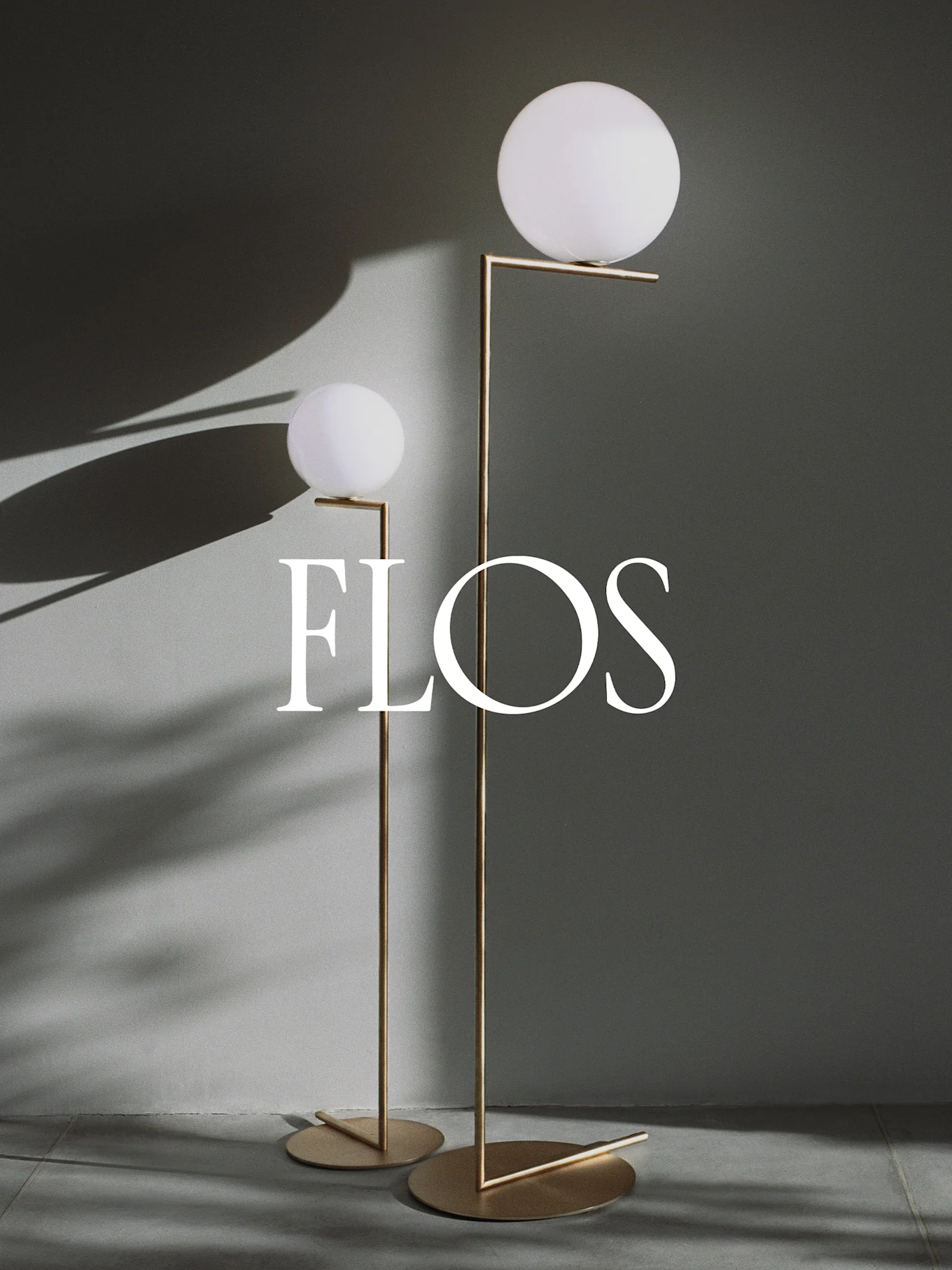 Two modern floor lamps with spherical white diffusers and gold metal frames, with the Flos logo.