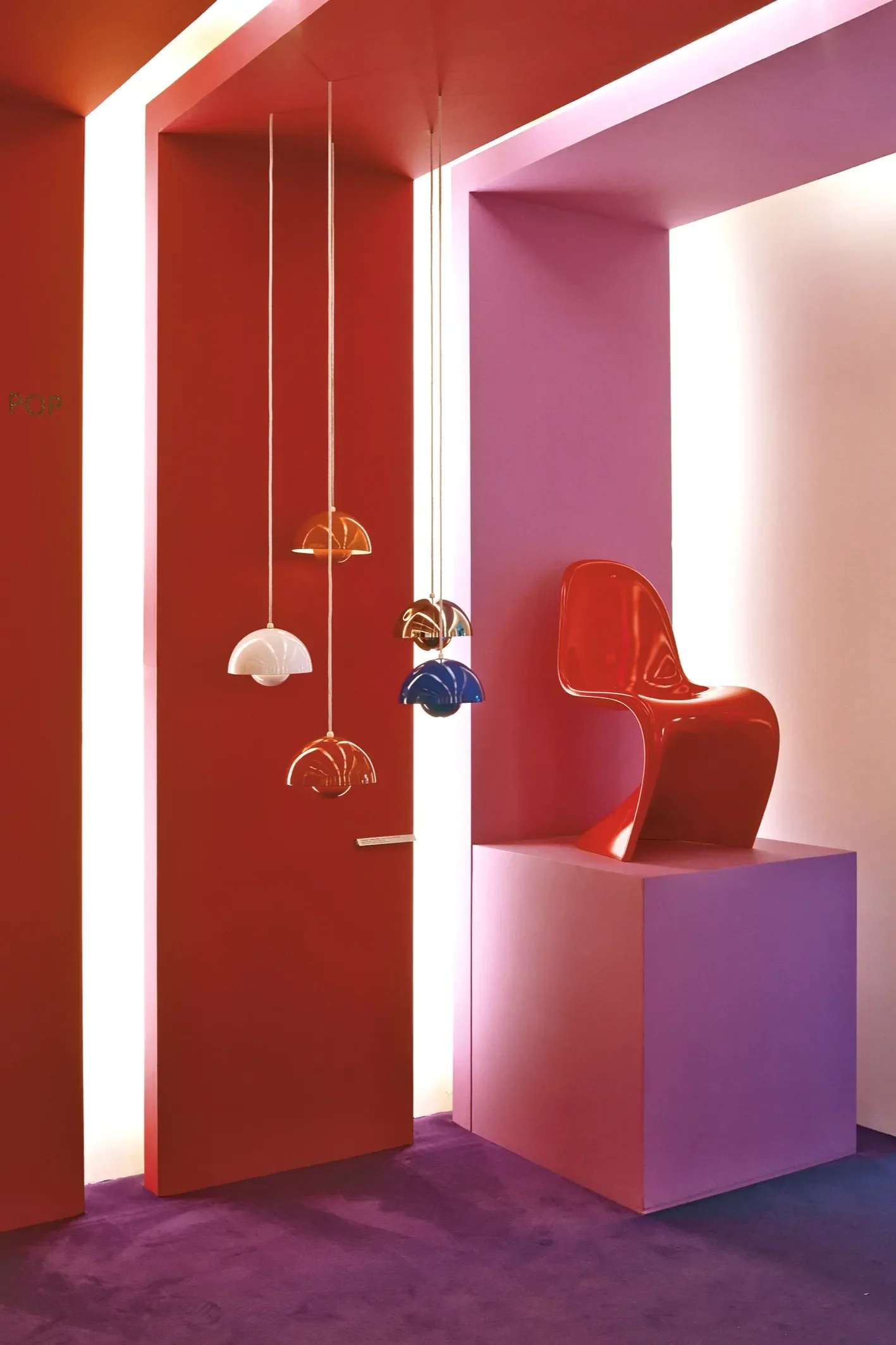 Several Flowerpot VP1 pendant lights hang from the ceiling in the Danish Design Museum, next to a red Panton chair.