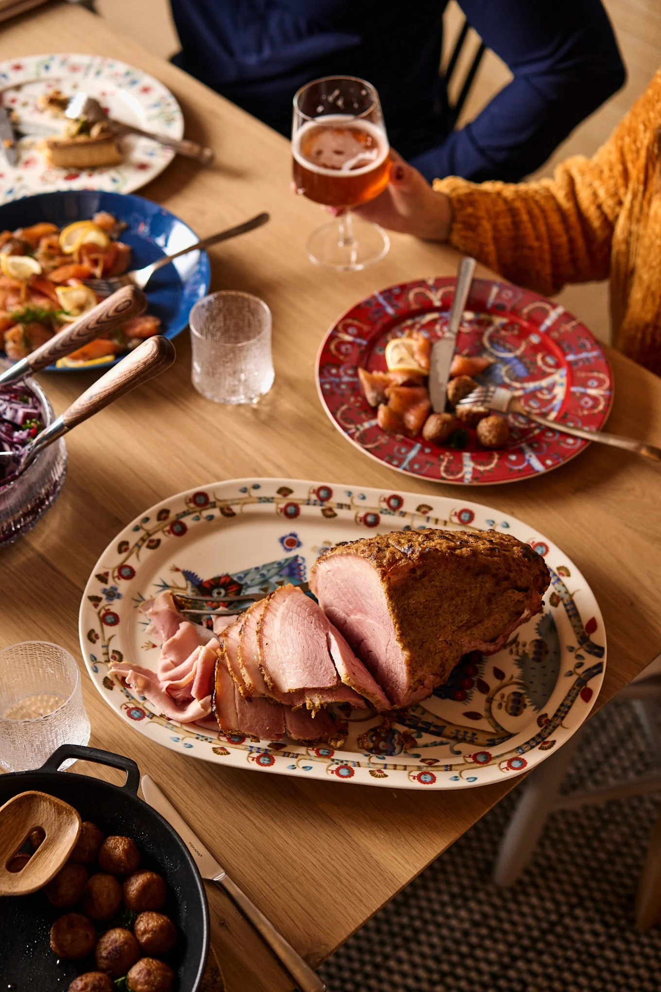 A sliced leg of ham stands on a traditional Nordic Christmas table.