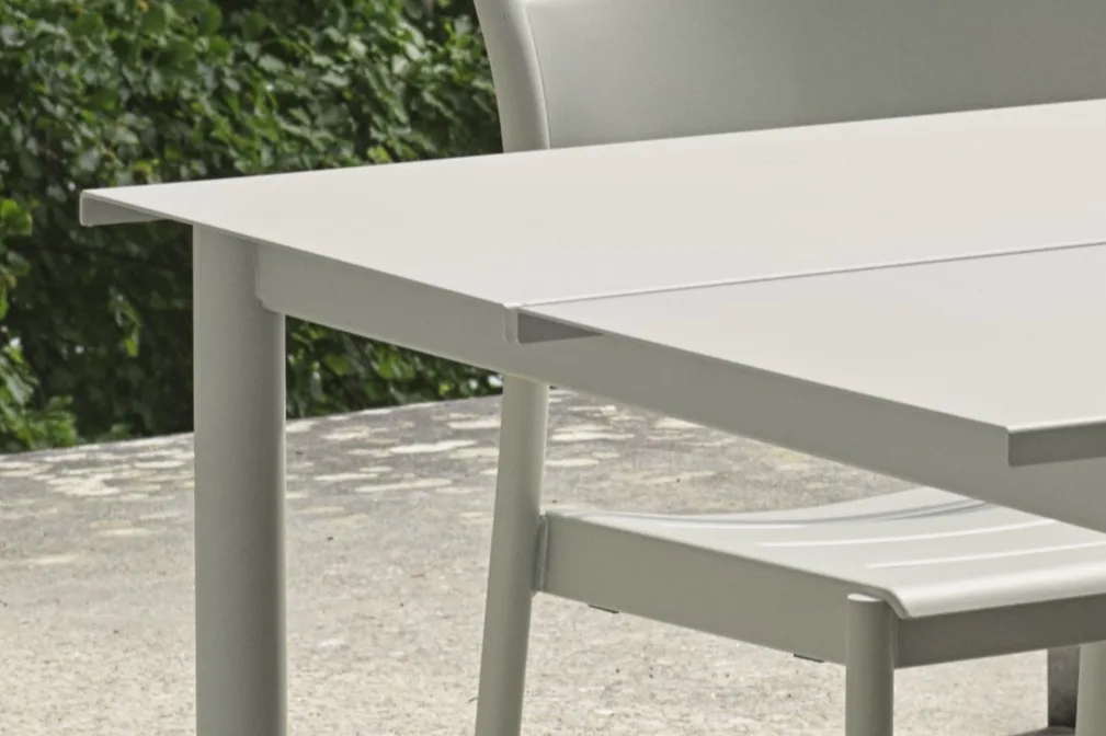 Modern light grey outdoor dining table and chair on a patio, with a subtle seam on the tabletop.