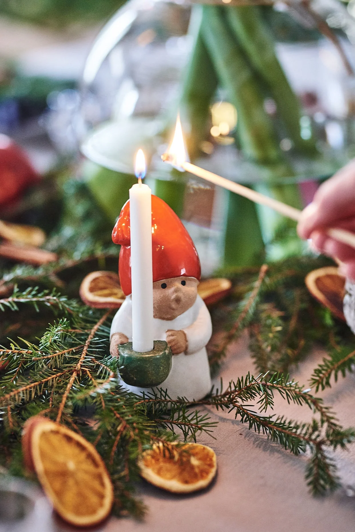 A small ceramic figure stands on a festively decorated table, while the candle he is holding is being lit. One of the oldest Swedish Christmas traditions. 